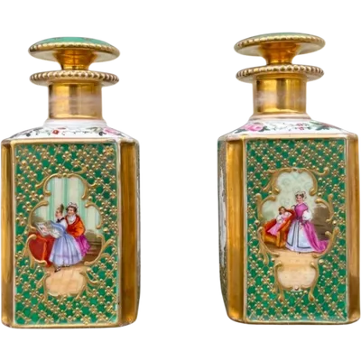 Pair of porcelain perfume bottles with female figures and floral and gold decorations.