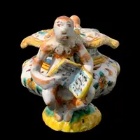 Saliera in maiolica con prese a forma di angeli che reggono dei libri e decoro a ‘raffaellesche