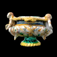 Saliera in maiolica con prese a forma di angeli che reggono dei libri e decoro a ‘raffaellesche