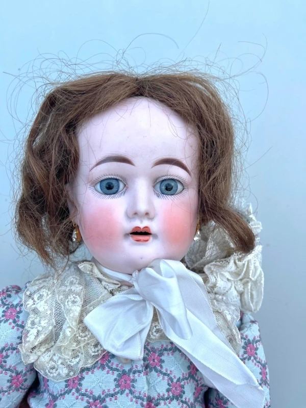 Doll with bisque head and paper mache body.Finely embroidered dress.