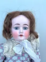 Doll with bisque head and paper mache body.Finely embroidered dress.