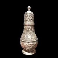 Silver sugar shaker featuring animal motifs, seed beads, and a medallion with engraved initials.