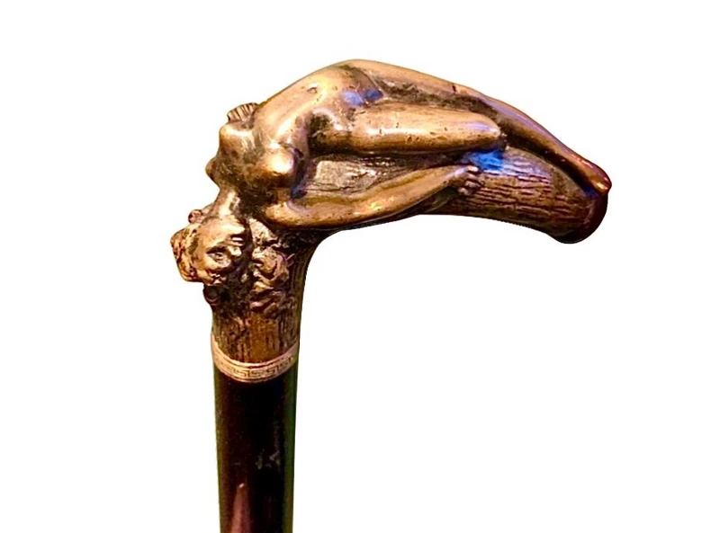 A walking stick with an erotic motif, featuring a bronze handle depicting a reclining nude woman.