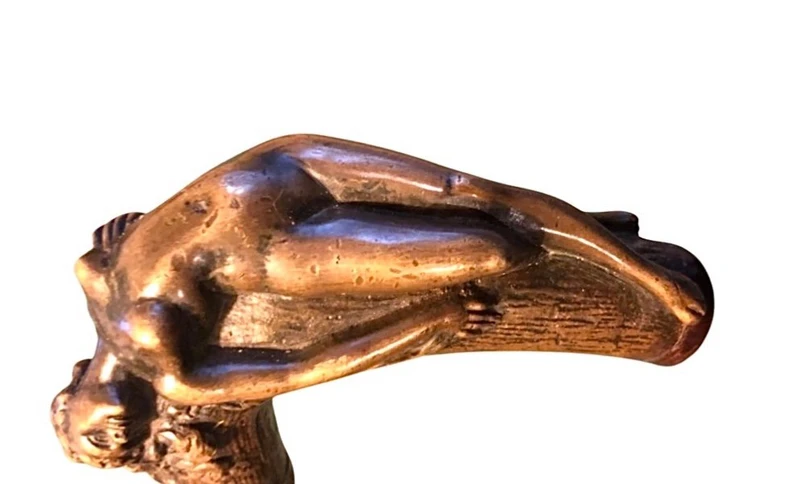 A walking stick with an erotic motif, featuring a bronze handle depicting a reclining nude woman.