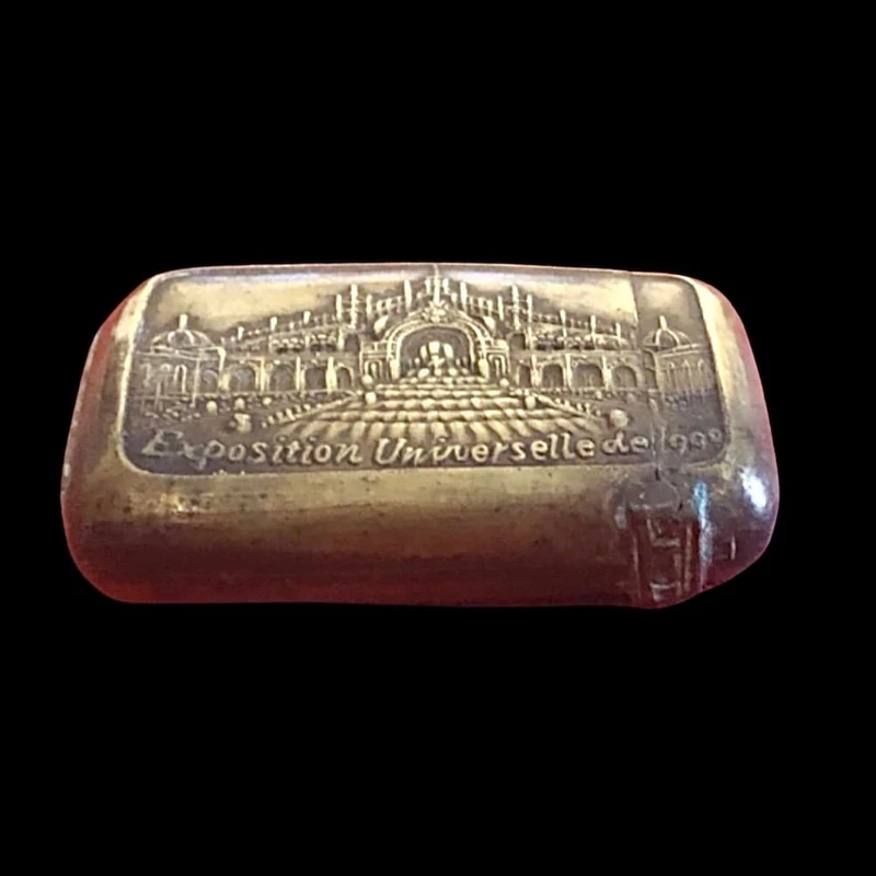 A small brass matchbox depicting the 1900 Paris World’s Fair.