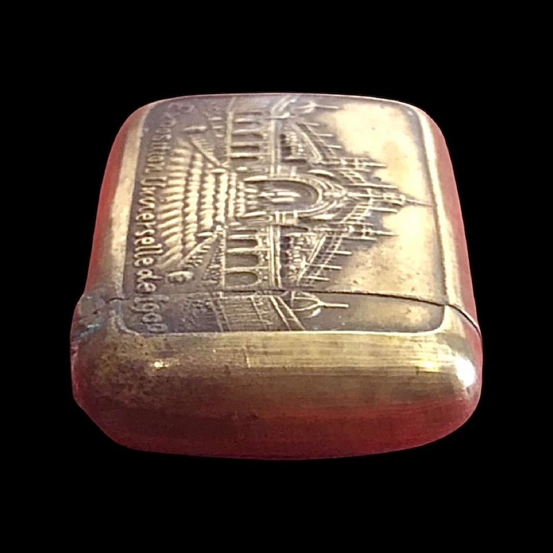 A small brass matchbox depicting the 1900 Paris World’s Fair.