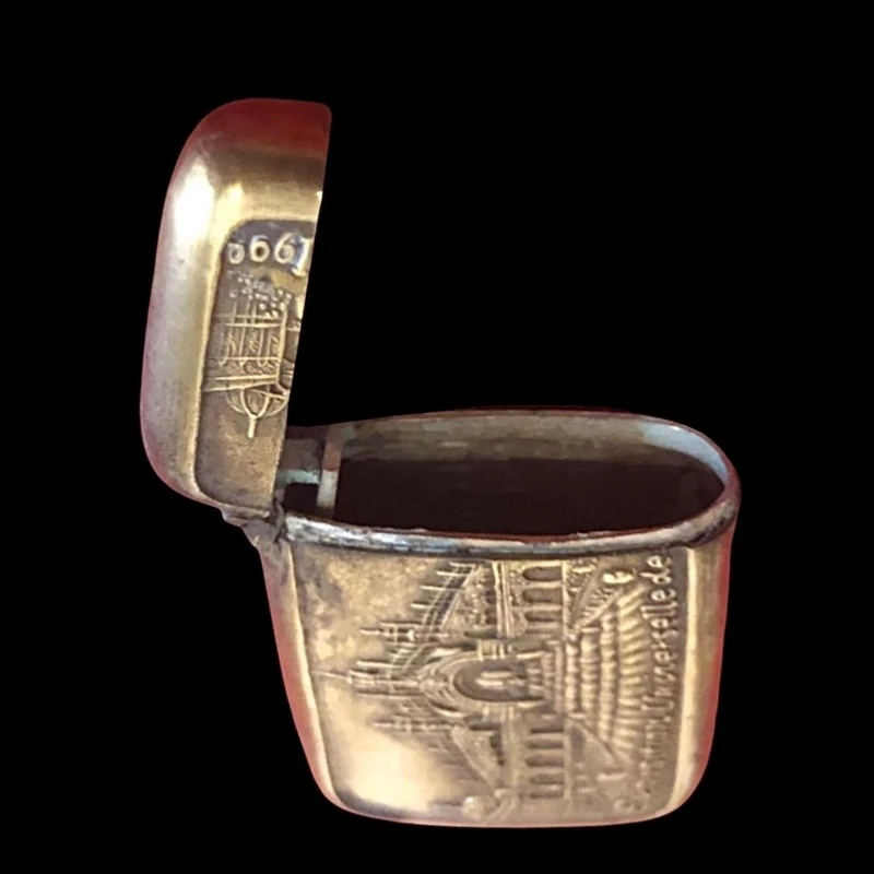 A small brass matchbox depicting the 1900 Paris World’s Fair.