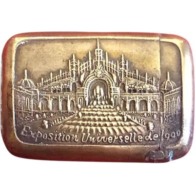 A small brass matchbox depicting the 1900 Paris World’s Fair.