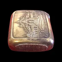A small brass matchbox depicting the 1900 Paris World’s Fair.