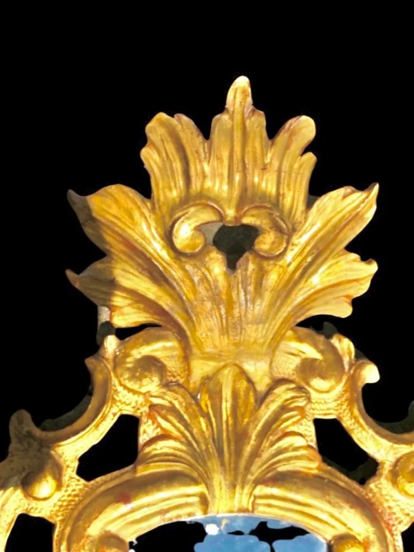Miroir en bois sculpté avec des motifs végétaux, des motifs rocaille et des feuilles d'or. Venise.