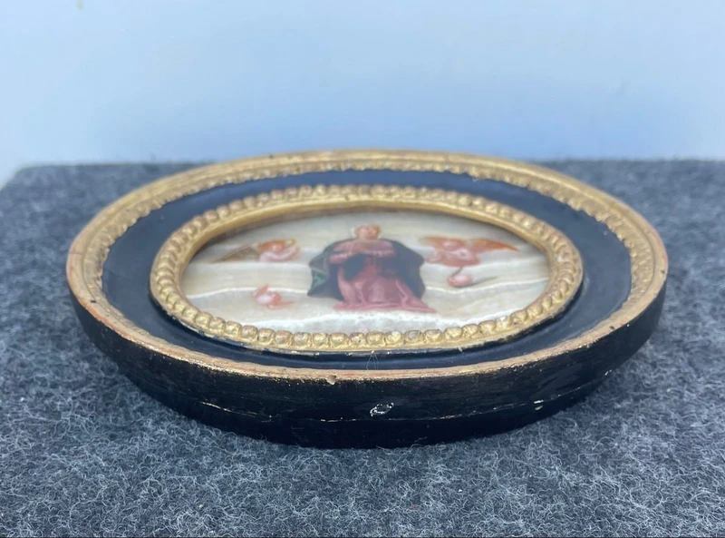 Oval alabaster painting depicting the Virgin Mary with angels and figures.