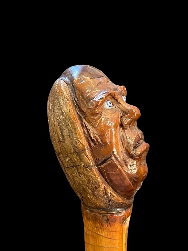 Cane with a curozo seed knob depicting a grotesque face. Glass eyes
