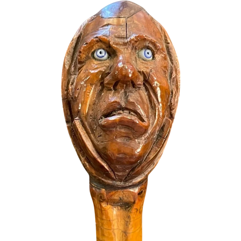 Cane with a curozo seed knob depicting a grotesque face. Glass eyes