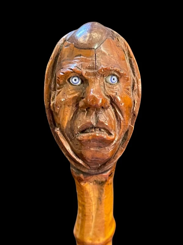 Cane with a curozo seed knob depicting a grotesque face. Glass eyes