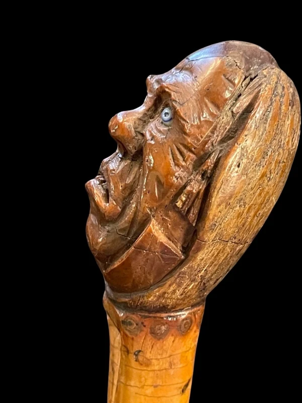 Cane with a curozo seed knob depicting a grotesque face. Glass eyes