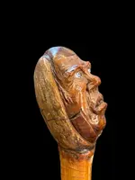 Cane with a curozo seed knob depicting a grotesque face. Glass eyes