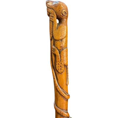 A traditional walking stick carved from a single piece of wood, featuring a jaguar attacking a snake.