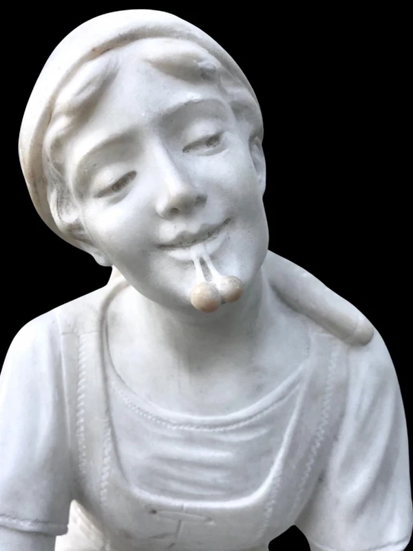A sculpture in white Carrara marble depicting a mother holding cherries and her child.