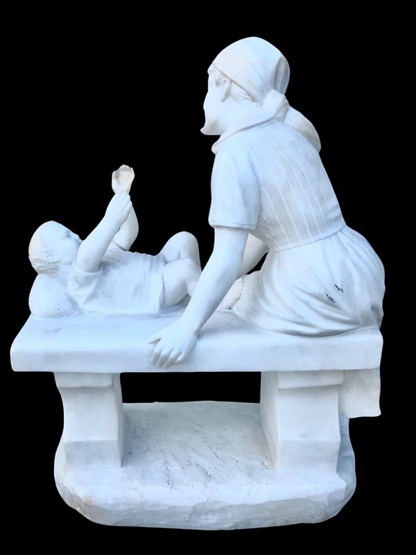 A sculpture in white Carrara marble depicting a mother holding cherries and her child.