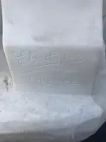 A sculpture in white Carrara marble depicting a mother holding cherries and her child.