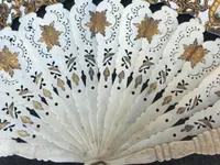 Fan with openwork, gilded bone ribs. Paper cover with watercolor prints
