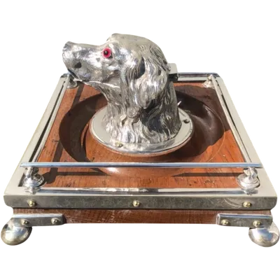 A four-legged inkwell made of Sheffield steel and oak, featuring a dog's head. England.