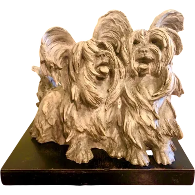 A terracotta sculpture depicting a pair of dogs, with a wooden base.