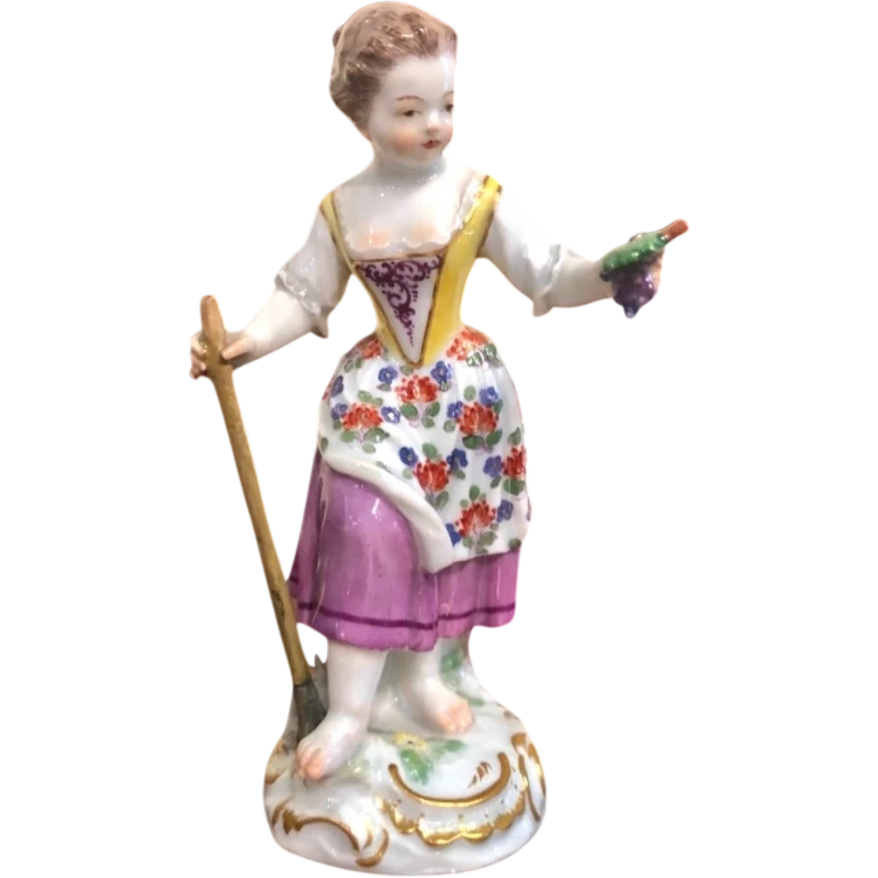 Sculturina in porcellana,figura di contadina con bastone e grappolo d’uva.Meissen.