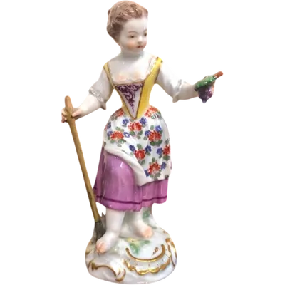Sculturina in porcellana,figura di contadina con bastone e grappolo d’uva.Meissen.
