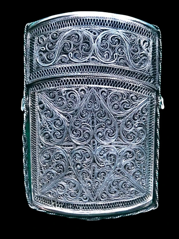 Silver filigree card holder featuring plant motifs and stylized scrolls.