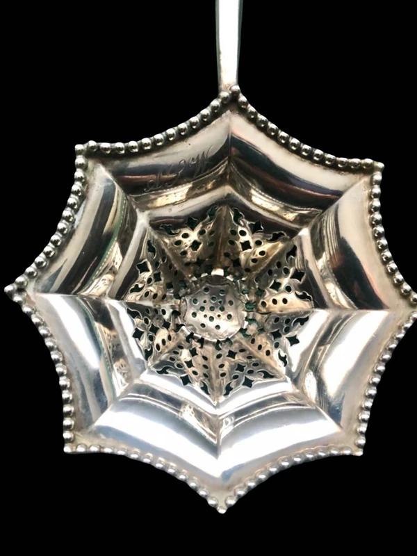 Silver tea strainer with an embossed eight-pointed geometric pattern. Ebony handle. Tiffany