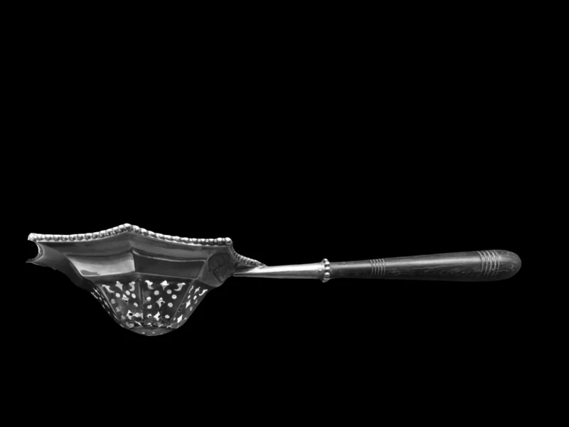 Silver tea strainer with an embossed eight-pointed geometric pattern. Ebony handle. Tiffany