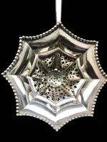Silver tea strainer with an embossed eight-pointed geometric pattern. Ebony handle. Tiffany