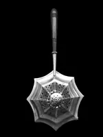Silver tea strainer with an embossed eight-pointed geometric pattern. Ebony handle. Tiffany