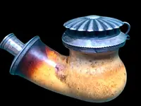 A globular-shaped pipe made of sea foam and silver with geometric patterns. Horn mouthpiece