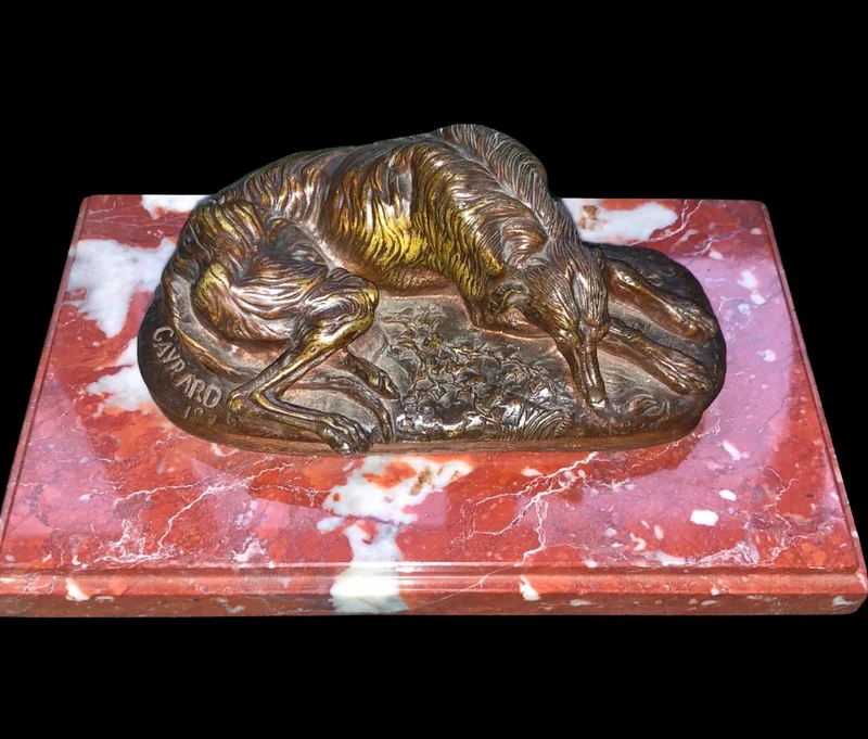 Bronze sculpture on a marble base depicting a sleeping greyhound. Signed