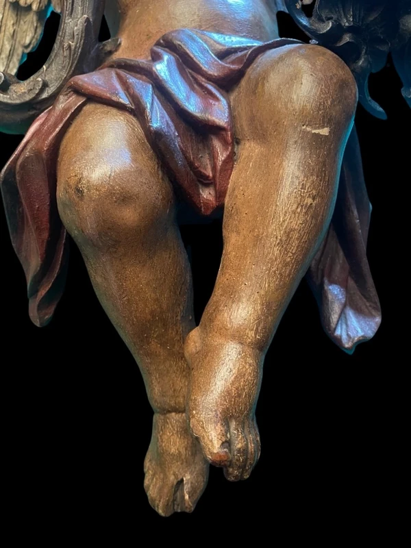 Polychrome wooden sculpture depicting an angel holding a candlestick and a rocaille shield