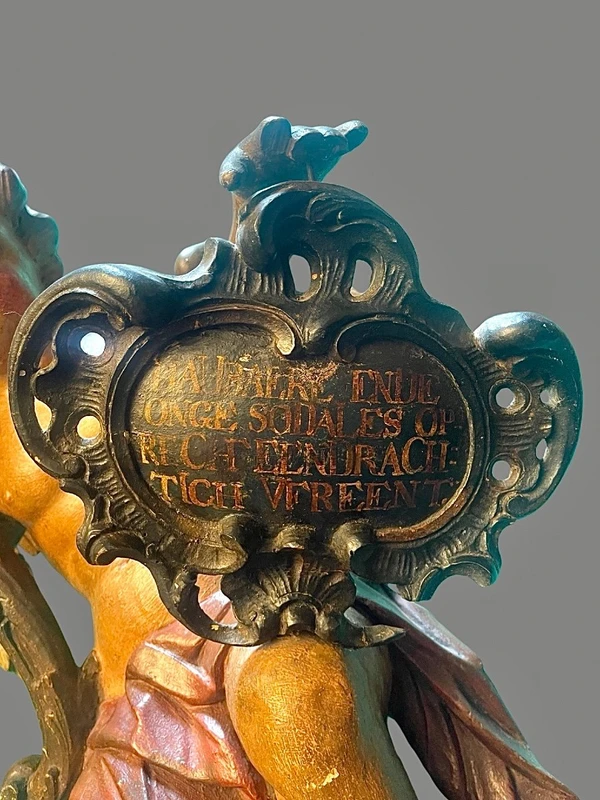 Polychrome wooden sculpture depicting an angel holding a candlestick and a rocaille shield