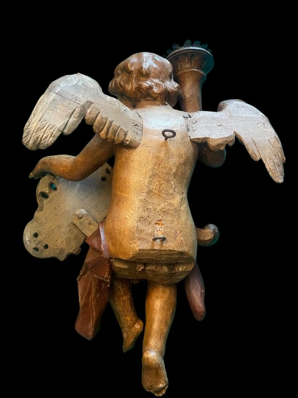 Polychrome wooden sculpture depicting an angel holding a candlestick and a rocaille shield