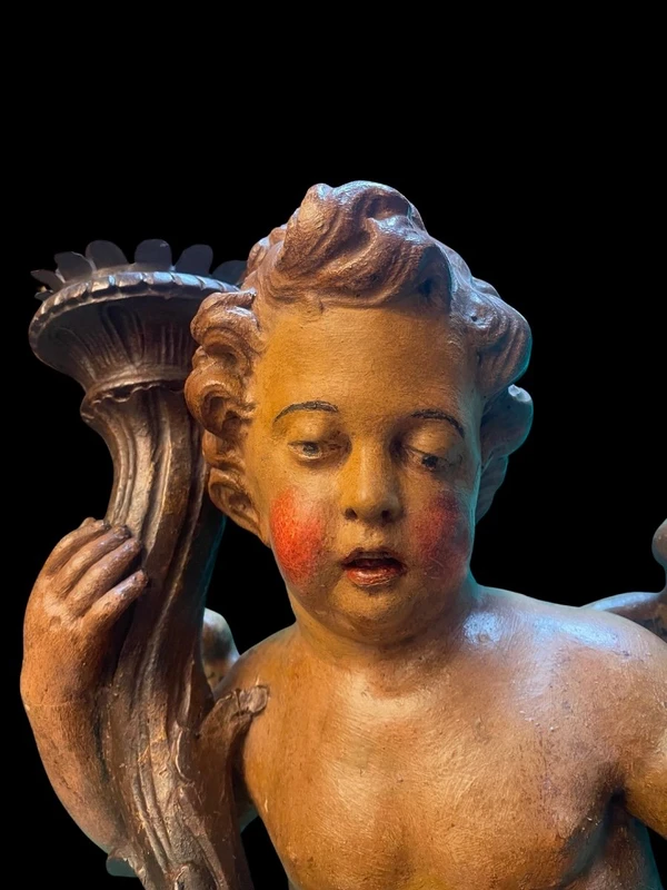 Polychrome wooden sculpture depicting an angel holding a candlestick and a rocaille shield