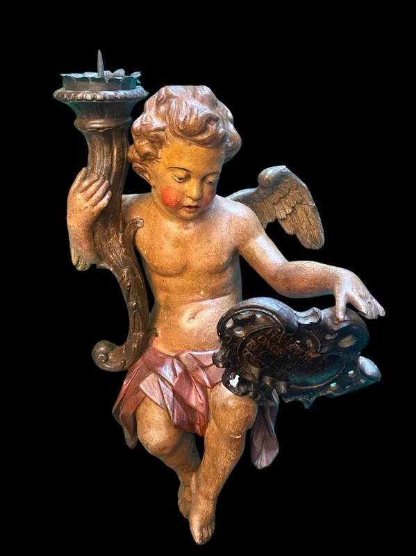 Polychrome wooden sculpture depicting an angel holding a candlestick and a rocaille shield