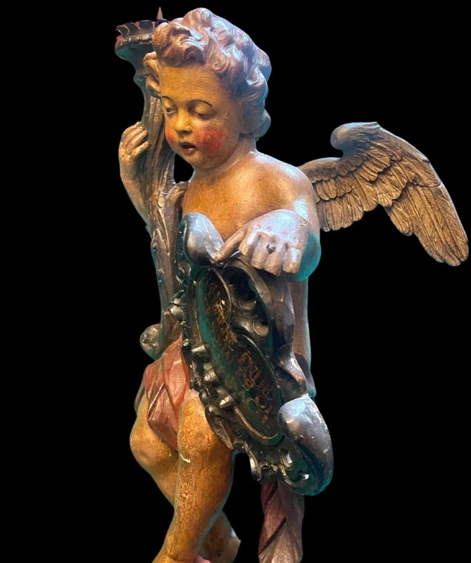 Polychrome wooden sculpture depicting an angel holding a candlestick and a rocaille shield