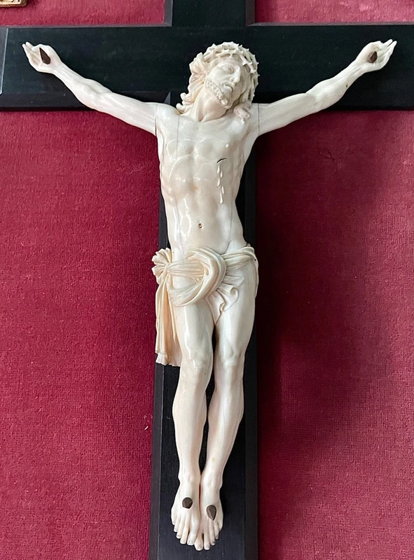 Cristo in avorio su croce in ebano e cornice sagomata in foglia oro.
