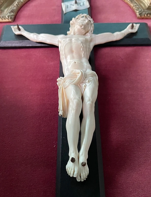 Cristo in avorio su croce in ebano e cornice sagomata in foglia oro.