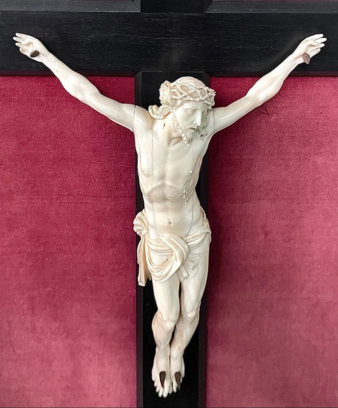 Cristo in avorio su croce in ebano e cornice sagomata in foglia oro.