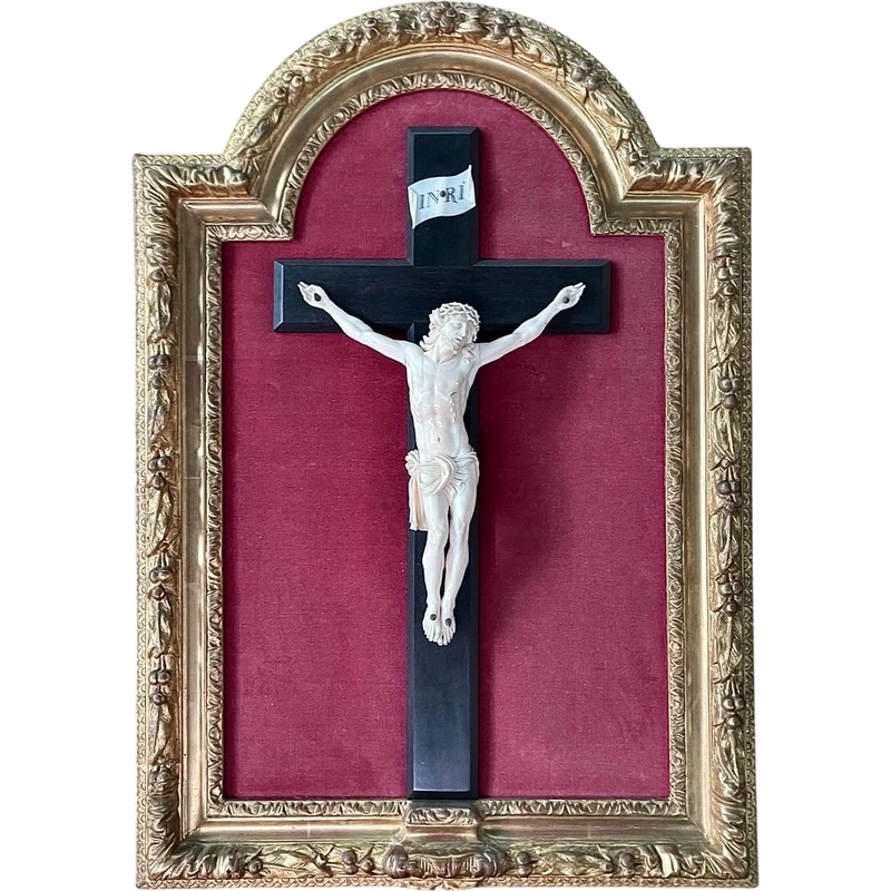 Cristo in avorio su croce in ebano e cornice sagomata in foglia oro.