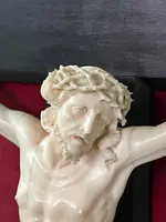 Cristo in avorio su croce in ebano e cornice sagomata in foglia oro.