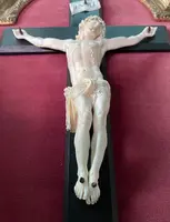Cristo in avorio su croce in ebano e cornice sagomata in foglia oro.