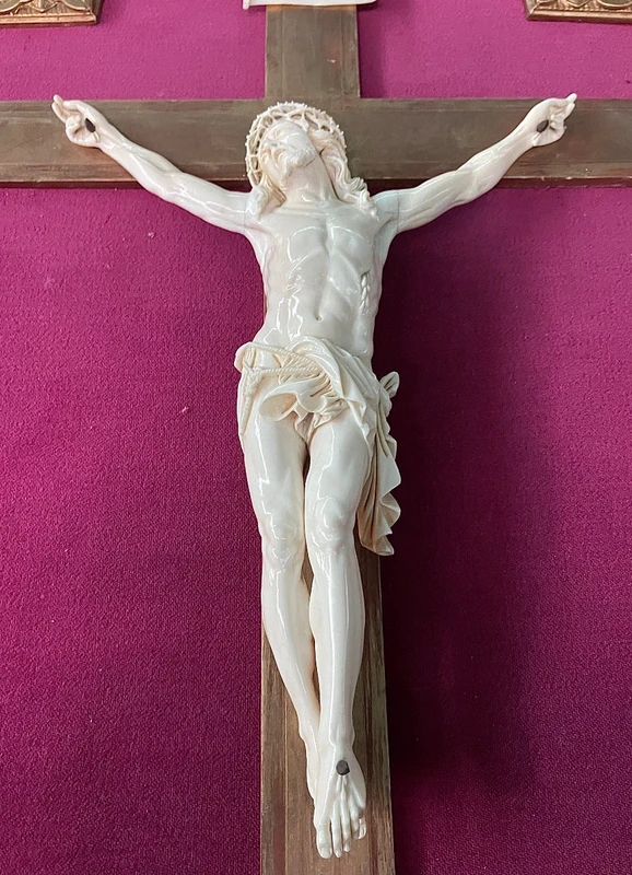 An ivory statue of Christ with a molded frame featuring floral motifs, rocaille, and gold leaf.