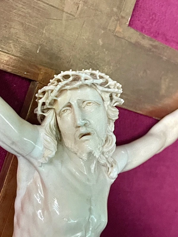 An ivory statue of Christ with a molded frame featuring floral motifs, rocaille, and gold leaf.